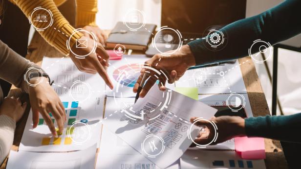 Mehrere Personen arbeiten gemeinsam an Design- und Farbschemata, umgeben von digitalen Symbolen für Technologie und Kommunikation.