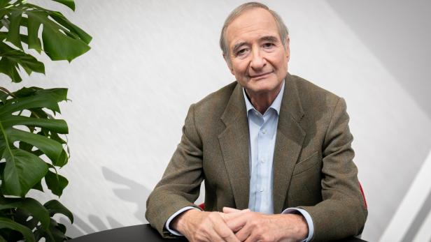 Christoph Leitl sitzt an einem runden Tisch und hat die Hände verschränkt.