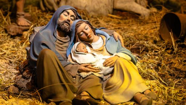 Eine Holzschnitzerei zeigt Josef, Maria und das Jesuskind schlafend im Stall.