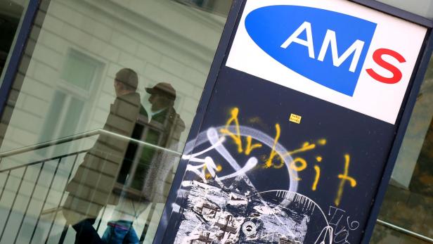 Ein Schild des AMS ist mit Graffiti beschmiert, im Fenster spiegelt sich ein Treppenhaus.