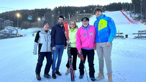 Fünf Personen stehen auf einer Skipiste.