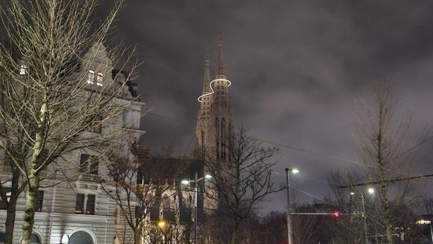 Die Votivkirche bei Nacht mit leuchtender Infinity-Lichtinstallation zwischen den Türmen.