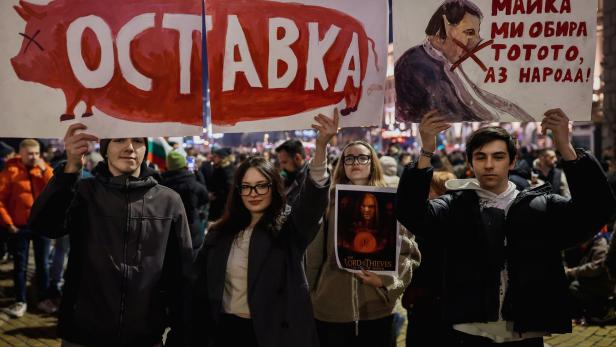 Junge Protestierende halten bei einer Demo am 10. Dezember ein Plakat mit einem Schwein hoch, auf dem „Rücktritt“ steht.  