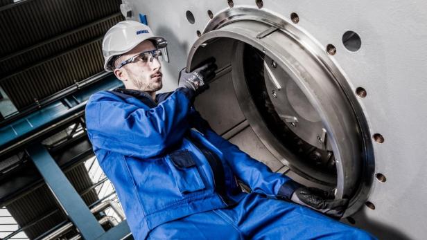 Andritz-Techniker mit Schutzhelm hantiert an einer Maschine.