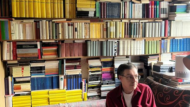 Franco Schedl sitzt vor seinen Büchern