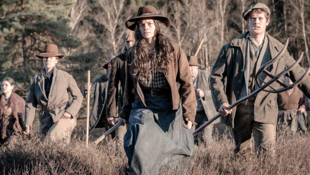 Mit Mistgabeln bewaffente Bauern ziehen durch eine Heidelandschaft