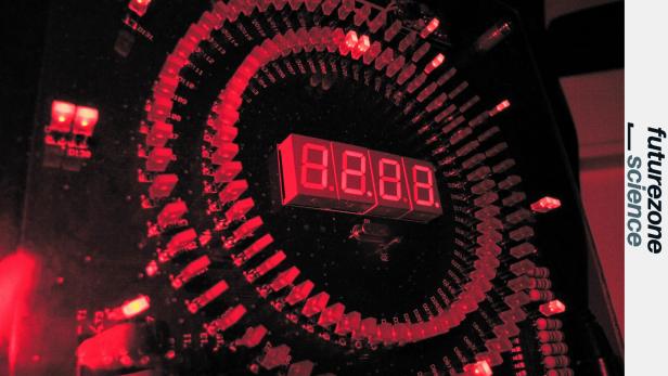Rotes LED-Display und elektronische Bauteile symbolisieren die technologische Entwicklung hochpräziser Uhren, wie sie für Atomkernuhren erforscht werden.