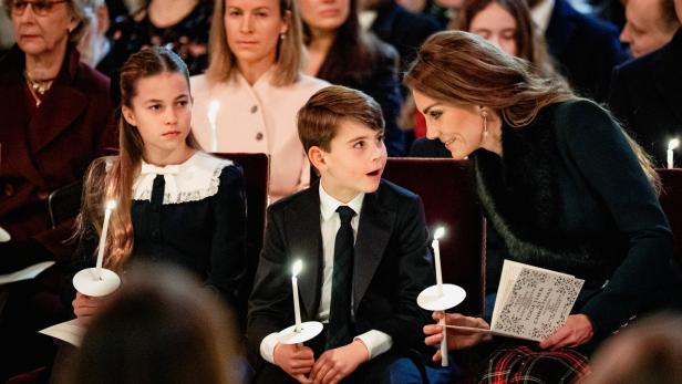 Kate mit Charlotte und Louis bei einer Weihnachtsveranstaltung, alle halten Kerzen.