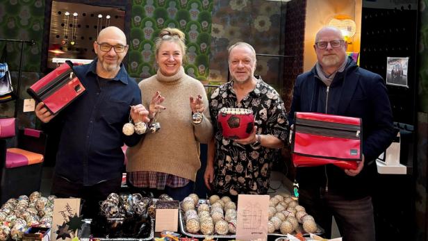 Vier Personen stehen hinter einem Tisch mit bunten Upcycling-Produkten und lächeln in einem Laden mit dem Schriftzug „gabarage“.