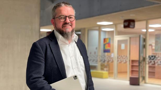 Markus Neuherz steht in der Aula der Schule, in der er unterrichtet.
