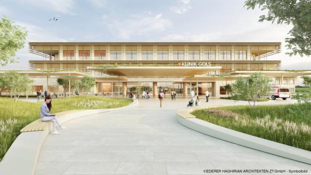 Moderne Klinik mit großer Glasfassade, umgeben von Grünflächen, Menschen sitzen und gehen auf dem Vorplatz, ein Rettungswagen steht rechts.