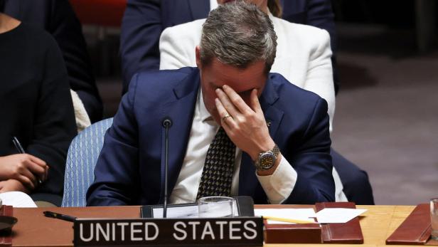 Mike Waltz im Anzug sitzt an einem Tisch mit dem Schild „United States“ und hält sich das Gesicht mit der Hand.