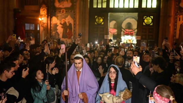 Eine Menschenmenge fotografiert Maria und Josef mit einem Jesuskind in einer Kirche.