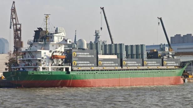Chinesisches Frachtschiff mit zahlreichen Containern und modularen Raketenwerfern an Deck.
