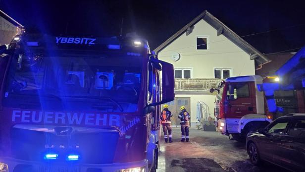 Feuerwehrautos und Einsatzkräfte vor einem Wohnhaus bei nächtlichem Brandeinsatz in Ybbsitz.