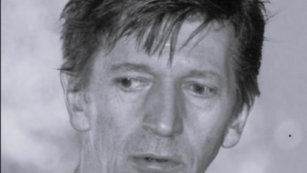 Porträt eines Mannes mit kurzem, dunklem Haar in Schwarz-Weiß.