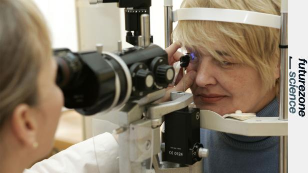 Eine Frau lässt bei einer Augenuntersuchung ihr Auge mit einem Spaltlampenmikroskop prüfen.