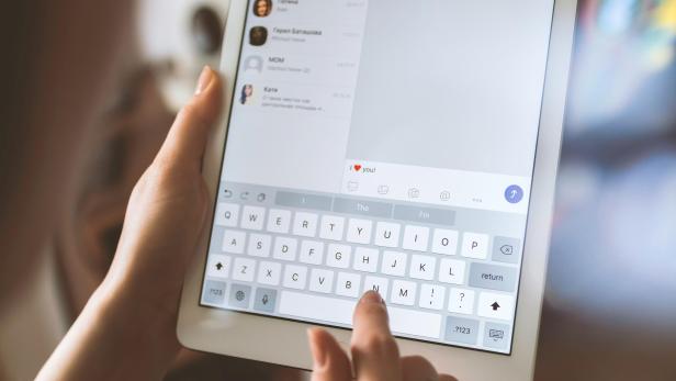 Person schreibt auf einem Tablet auf Englisch die Nachricht "Ich liebe dich"