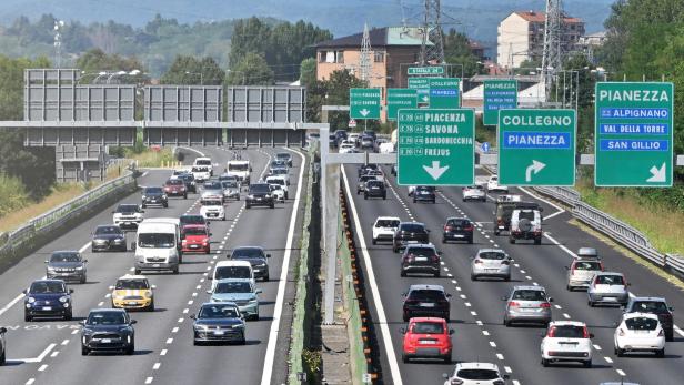 Auf einer Autobahn fahren viele Autos unter Wegweisern nach Pianezza, Collegno und Piacenza.