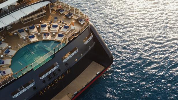 Vogelperspektive auf ein Reiseschiffes mit Pool auf dem Deck und Sonnenliegen