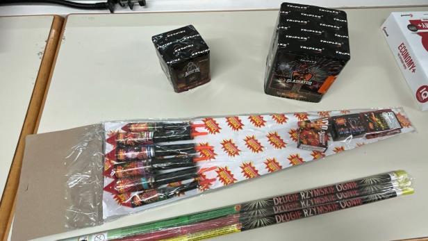 Mehrere Feuerwerkskörper, darunter Raketen, Batterien und römische Lichter, liegen auf einem Tisch.