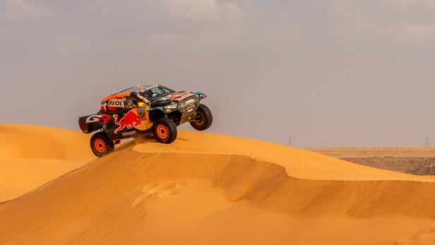 Ein Auto fährt bei der Rallye Dakar über eine Sanddüne.