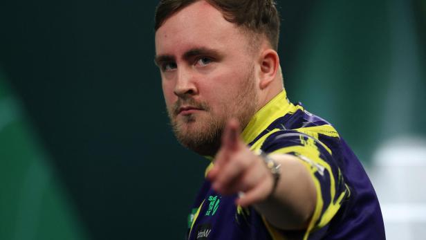 Luke Littler zeigt mit dem Finger nach vorne.