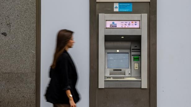 Frau geht an Bankomat vorbei.