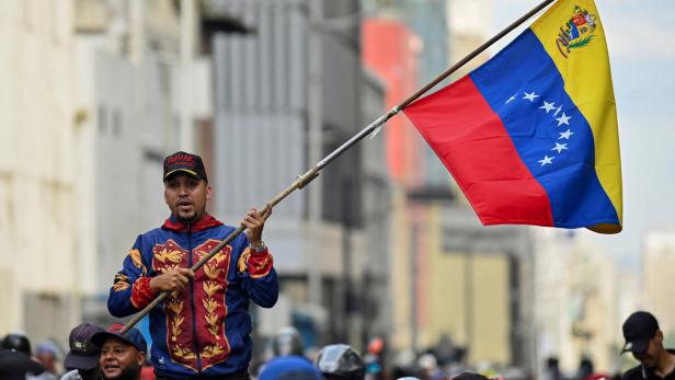 ein Mann schwingt eine venezolanische Fahne