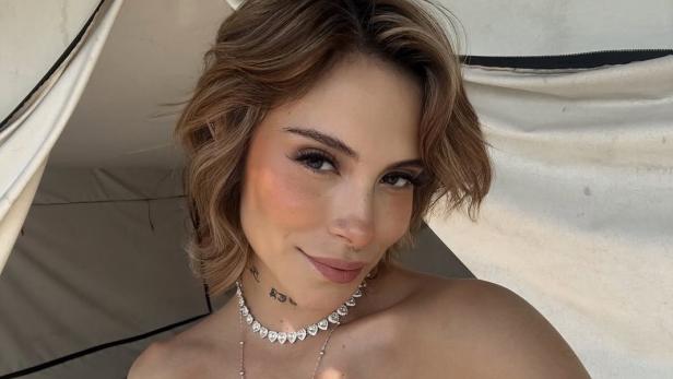 28-jährige Frau mit kurzen blonden Haaren lächelt in die Kamera für ein Selfie