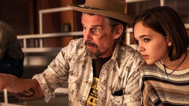 Ein Mann mit Hut und Bart zeigt einer jungen Frau neben ihm etwas, beide schauen konzentriert in dieselbe Richtung.