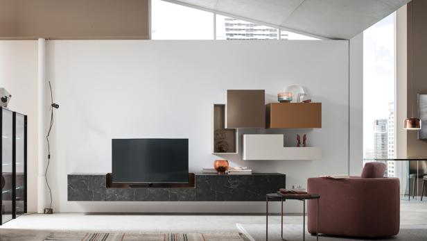 Ein modernes, helles Wohnzimmer mit Sideboard und Fernseher und einem braunen Wohnzimmersessel.