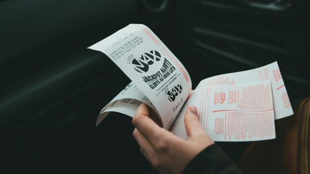 Eine Person hält mehrere Lottoscheine in der Hand.