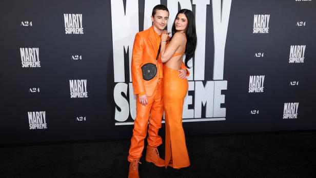 Timothée Chalamet und Kylie Jenner posieren gemeinsam in oranger Kleidung.