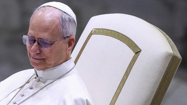 Der Papst sitzt auf einem verzierten Stuhl.