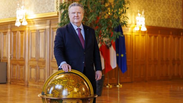 Michael Ludwig im Anzug steht in einem prunkvollen Saal neben einem großen Globus.