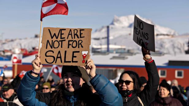 Demonstranten halten Schilder mit Aufschriften wie "We are not for sale" und die Flagge Grönlands hoch.