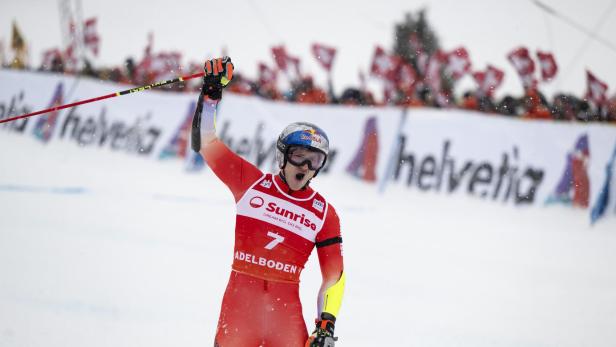 Ein Skirennläufer in rotem Anzug jubelt vor einer Zuschauermenge in Adelboden.