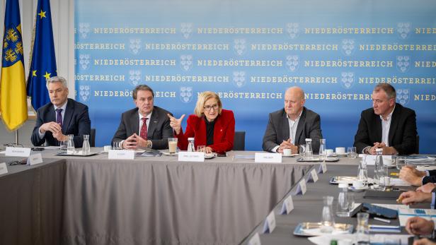 Eine Gruppe von Personen, darunter Mikl-Leitner, sitzt an einem Tisch vor einem Hintergrund mit dem Schriftzug "Niederösterreich".