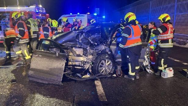 Einsatzkräfte stehen um ein Unfallfahrzeug herum.