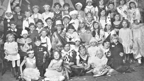 Viele Kinder in fantasievollen Kostümen sitzen und stehen in mehreren Reihen für ein Gruppenporträt zusammen.