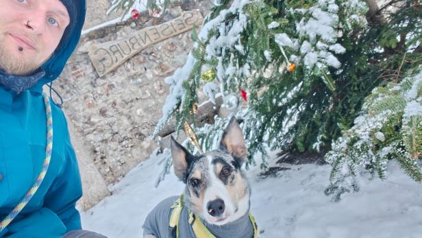 Ein Mann mit einem Hund schaut in die Kamera