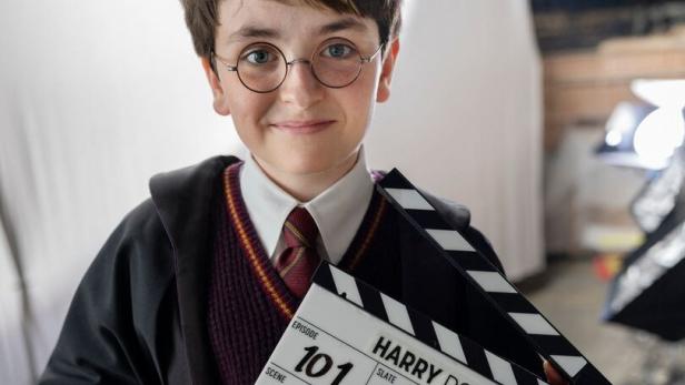Ein junger Schauspieler im Harry-Potter-Kostüm hält eine Filmklappe mit der Aufschrift "Harry Potter, Episode 101".
