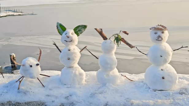 Mehrere Schneemänner stehen auf einer Brücke an der Alster in Hamburg