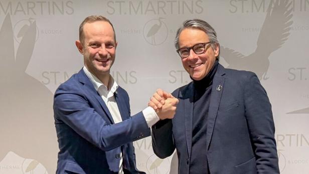 Zwei Männer geben sich vor dem "St. Martins Therme & Lodge"-Logo die Fäuste.