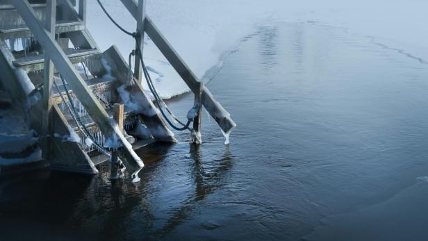 Holztreppe führt in halb zugefrorenen See