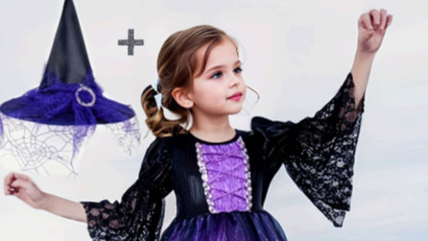 Mädchen im lila-schwarzen Hexenkostüm mit passendem Hexenhut am Strand.