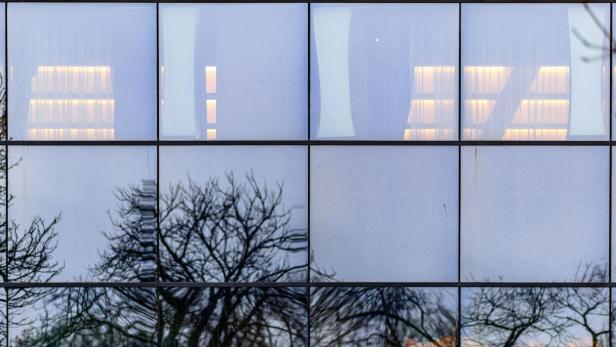 eine verglaste Fassade, in der sich Bäume spiegeln