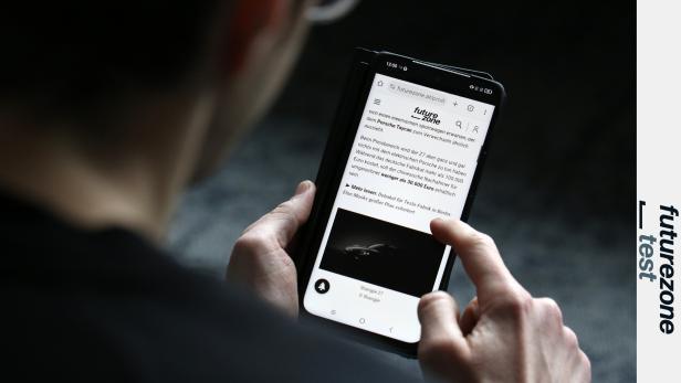 Ein Mann hält das Smartphone TCL Nxtpaper 60 Ultra und liest etwas im ePaper-Modus