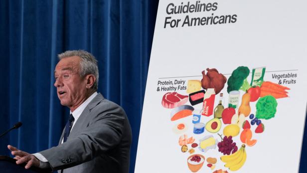 US-Gesundheitsminister Kennedy spricht am Rednerpult neben einer Grafik mit Ernährungsempfehlungen für Amerikaner.